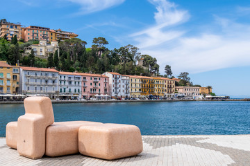 Bench on seafront in Porto Santo Stefano village in a sunny day with beautiful cloudy sky....