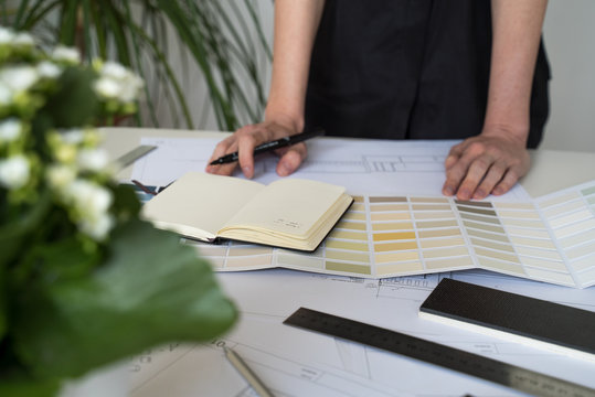 The interior designer selects wall paint samples. Designer at work. Architect desk. Decoration. Design project blueprints. Plans and drawings. Grey stone. Paint catalog. Decorative material. Flatlay