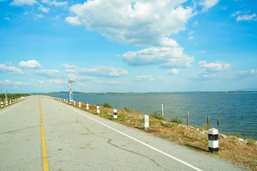 Obraz premium Blue clouds sky and ahead long empty asphalt with black and white concrete kilometre sign pole along seaside road ,blue sea mountain landscape in sunny day in Thailand.