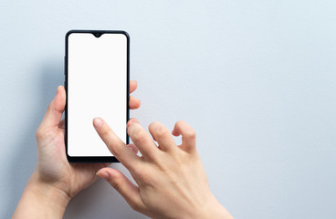 Concept of use of the smartphone. A smartphone with a white blank screen in the hand of a woman.