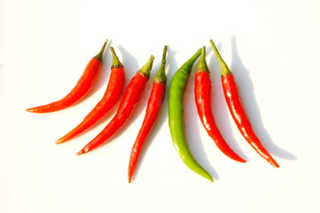 In the photo, red and green chili peppers. Seven pods on a white background.