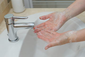 female hands in soapy foam under tap water close-up