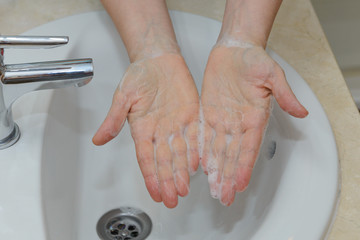 female hands in soapy foam under tap water close-up