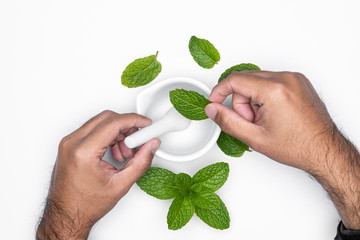 Man hand with mortar grind and herbs isolated on white background. For copy space.
