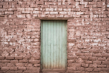 Fototapeta na wymiar teal wooden door in grungy brick house in desert
