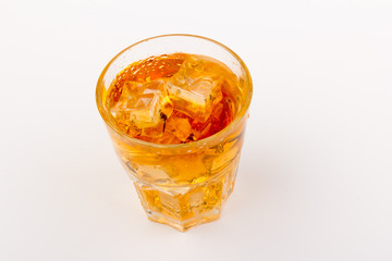 Glass of scotch whiskey and ice over white background.