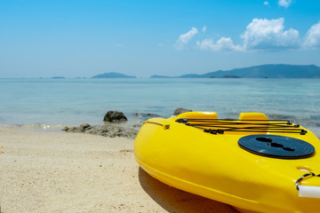 Fototapeta na wymiar Yellow kayak boat on beautiful beach with ocean and sky background