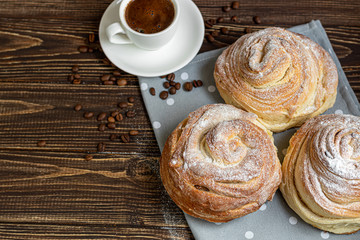 Bakery products with raisins and dried fruits are located on a dark wooden background. Sprinkled with icing sugar. Kraffins. Easter food.