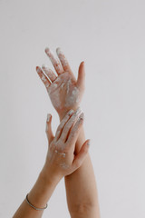 female hands smeared with white paint on a white background