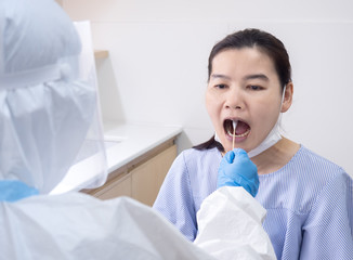Woman doctor in personal protective suit using cotton swab to do buccal swab sample collection for coronavirus testing from patient at risk of coronavirus infection. Covid-19 and vaccination concept