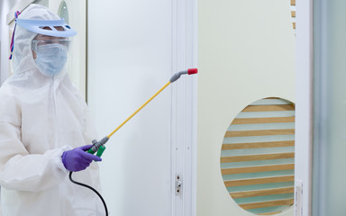 Asian women wear personal protective suits or PPE, goggles, masks, and gloves making disinfection and decontamination on public place. to reduce spreading of disease. Covid-19, coronavirus concept