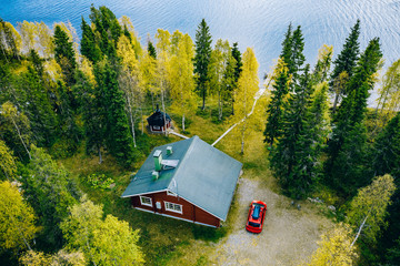 Aerial top view of log cabin or cottage with sauna in spring forest by the lake in Finland