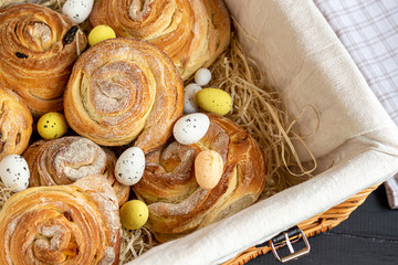 Bakery products with raisins and dried fruits are located on a dark wooden background. Sprinkled with icing sugar. Kraffins. Easter food.
