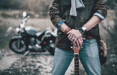 Young beard man on a bike in mountances with guitar