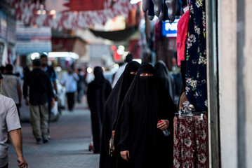 women in burkahs shopping in arab street market