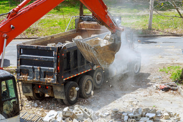 Excavator scoop truck loading a construction waste into reinforced concrete recycling garbage