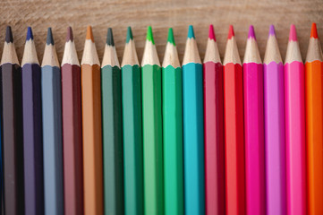 Rainbow of colored pencils on wood background