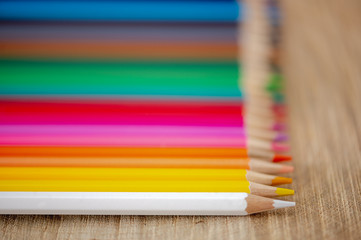 Fototapeta premium Rainbow of colored pencils on wood background