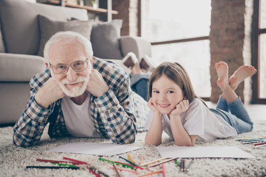 Closeup photo of grandpa spend time little granddaughter together lying comfy fluffy floor carpet painting colorful pencils best friends stay home quarantine living room indoors