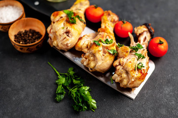Fototapeta na wymiar grilled chicken legs with spices on a knife on a stone background