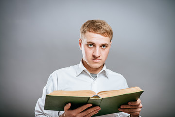 pensive young business man reding a book. on a gray background