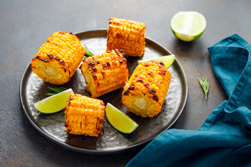 Roasted or grill corn cob with olive oil and salt on a black plate.