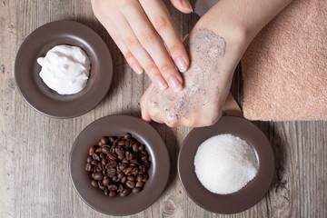 A woman applies a natural coffee scrub to the skin. Homemade scrub made of sugar, salt, cream and coffee. Beauty, Spa, skin care, aromatherapy. Moisturizing, peeling, exfoliation