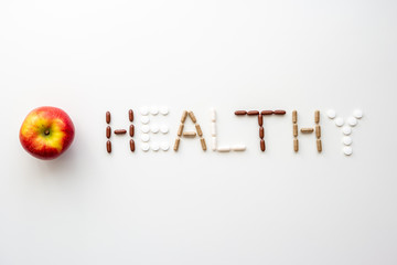 The word healthy spelled out from different types of medical pills and capsules set of bright white...