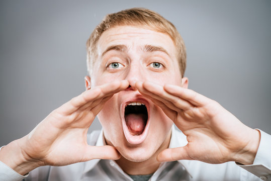 Photo of shouting man with his palms open by mouth looking upwards
