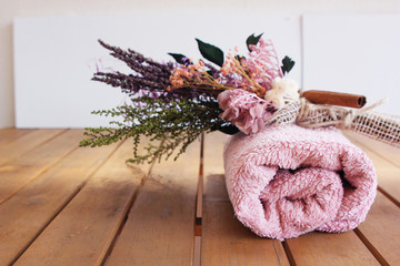 pink twisted towel on a brown wooden table with a bouquet of dried flowers