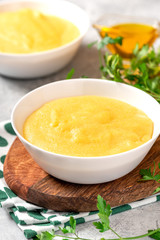 Traditional cooked polenta in a white bowl on a gray concrete table. Italian food.