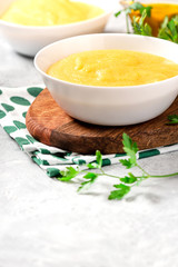 Traditional cooked polenta in a white bowl on a gray concrete table. Italian food.