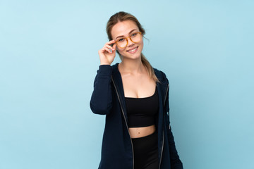 Teenager Russian girl holding mat isolated on blue background with glasses and happy