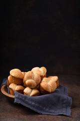 Freshly Baked Cloverleaf Rolls in a Wooden Bowl with Dark Blue Napkin; Dark Rustic Background