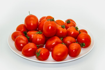 Ripe fresh red cherry tomatoes on a white plate against white background.  Beautiful and healthy fresh cherry tomatoes without GMO.