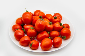 Ripe fresh red cherry tomatoes on a white plate against white background.  Beautiful and healthy fresh cherry tomatoes without GMO.