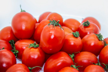 Ripe fresh red cherry tomatoes on a white plate against white background.  Beautiful and healthy fresh cherry tomatoes without GMO.