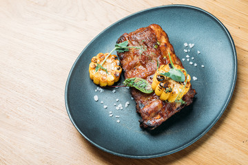 grilled pork ribs served on a blue plate with corn and salt