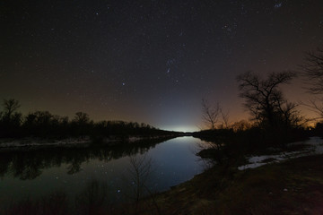 Bright stars of the night sky over the river. Landscape with a view of outer space.
