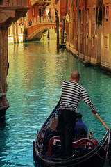 Fototapeta na wymiar Venice gondolier rides tourists through the canals of Venice.