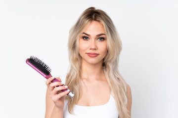 Teenager blonde girl over isolated white background with hair comb