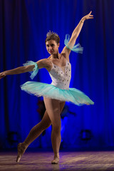Young girl ballerina in a light blue dress tutu dancing performance of a ballet on stage in a theater © Kozlik_mozlik