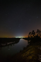 Bright stars of the night sky over the river. Landscape with a view of outer space.