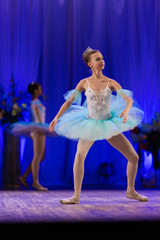 Young girl ballerina in a light blue dress tutu dancing performance of a ballet on stage in a theater © Kozlik_mozlik