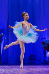 Young girl ballerina in a light blue dress tutu dancing performance of a ballet on stage in a theater © Kozlik_mozlik