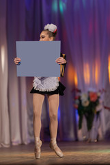 A young girl ballerina in a school uniform with an alphabet book in her hands dances a ballet performance on stage in a theater on a red background © Kozlik_mozlik