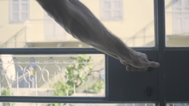 Closing a glass door. Masculine  veiny arm shutting the entrance. Man shutting door