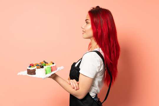 Pastry chef holding a muffins isolated on pink background in lateral position