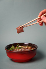noodle soup sliced ​​meat with chopsticks, asian food, gray background