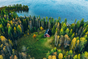 Aerial top view of red log cabin or cottage with sauna in spring forest by the lake in Finland - obrazy, fototapety, plakaty